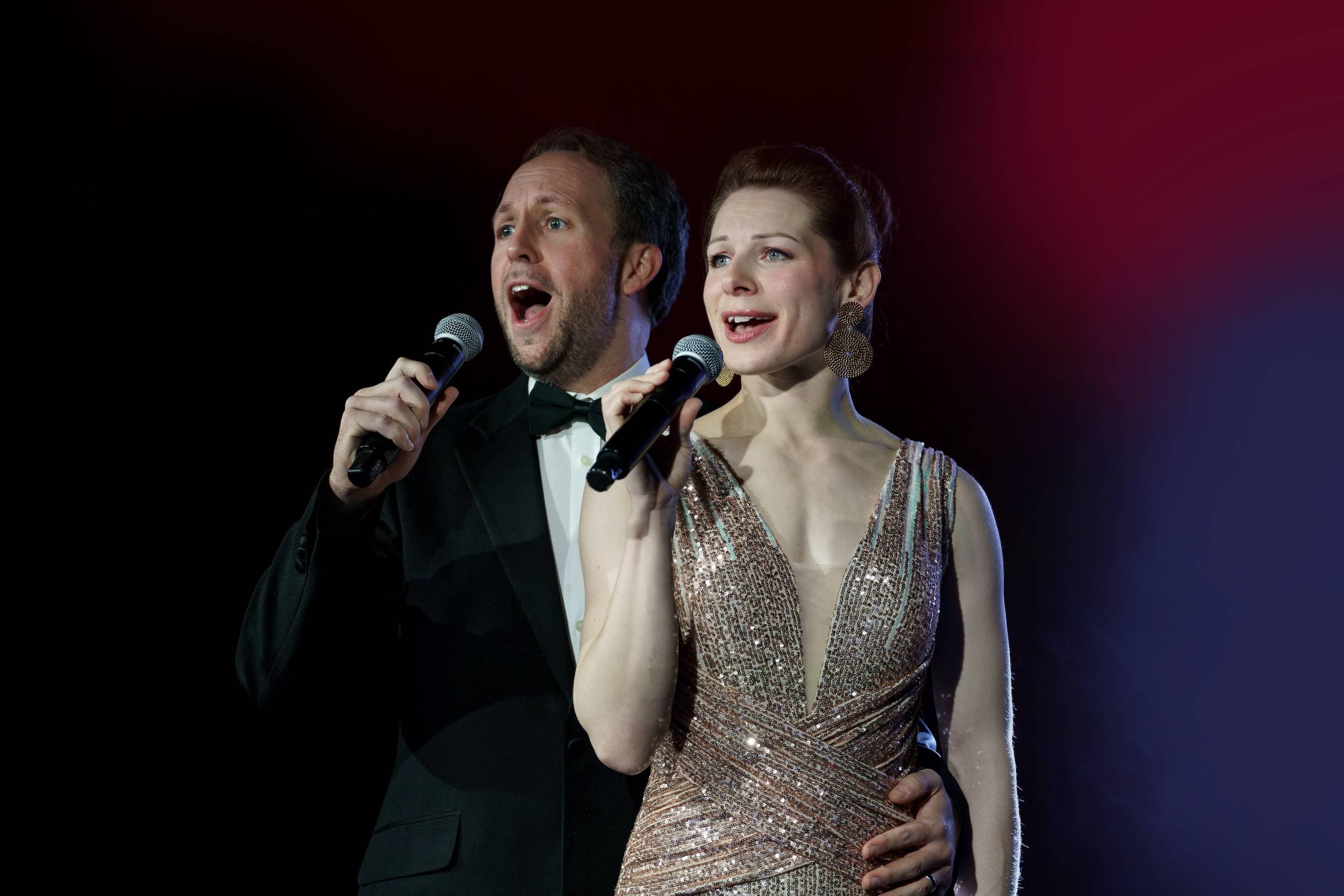 Rachel Manchester and Peter Manchester singing a theatrical song in elegant costumes